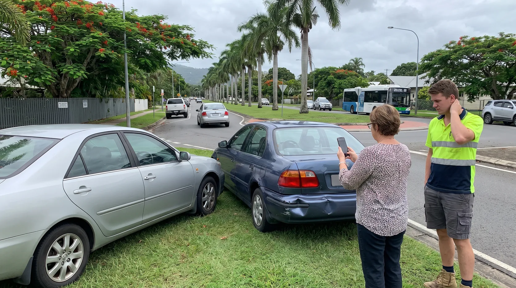 A woman photographing a dented bumper beside two cars pulled over after a minor crash, with a young driver nearby