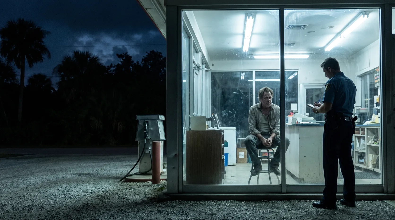 A police officer taking notes from a service station attendant at night